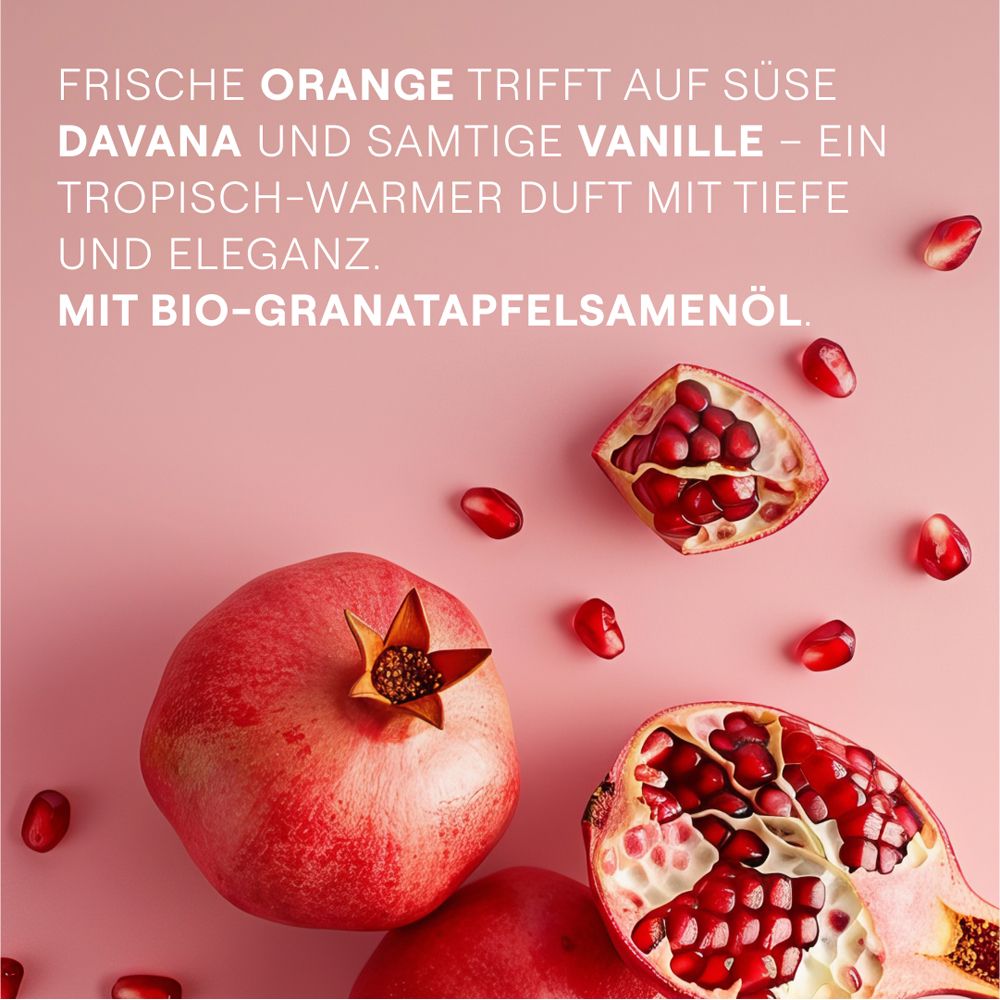 Granatapfel-Hälften und -Kerne auf rosa Hintergrund. Text: Frische Orange, Davana, Vanille. Mit Bio-Granatapfelsamenöl.