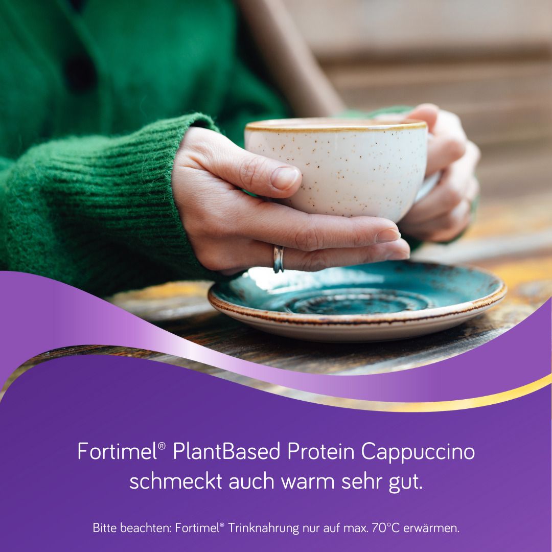 Hände halten eine Tasse Kaffee. Fortimel PlantBased Protein Cappuccino schmeckt warm sehr gut.