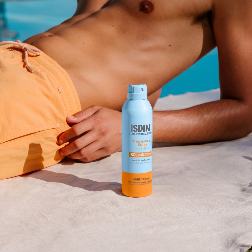 Mann am Pool mit ISDIN Transparent Spray. Blaue und orangefarbene Sprühflasche.