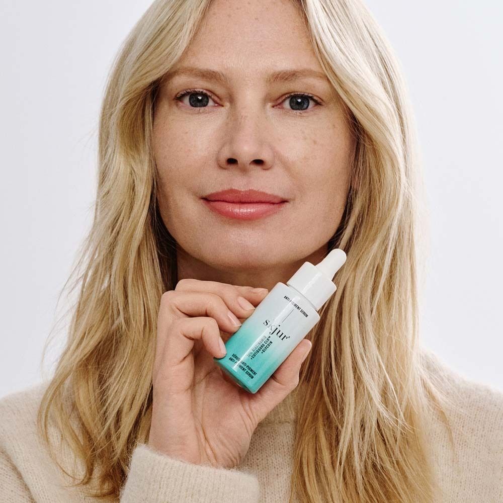 Frau hält skjur® Anti-Pigment Serum. Flasche mit Pipette. Blondes Haar.