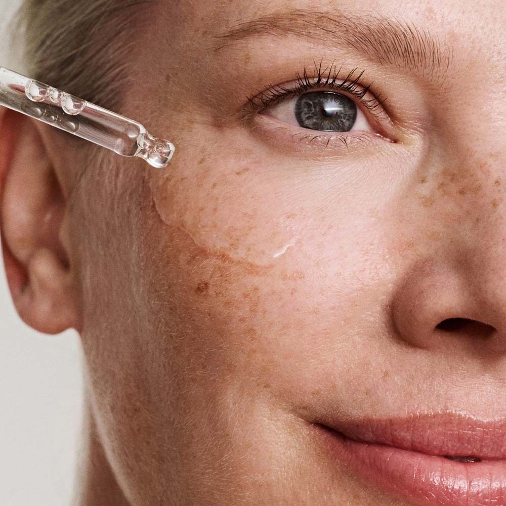 Nahaufnahme: Serum wird auf Haut aufgetragen. Pipette. Haut mit Sommersprossen.