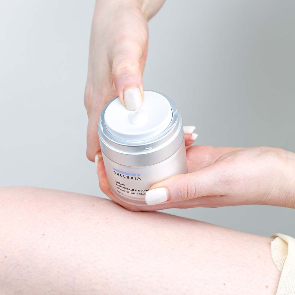 Hände halten Creme-Dose. Aufschrift: Cellexia, Crème Anti-Cellulite Avancée, Advanced Anti-Cellulite Cream, 50ml.