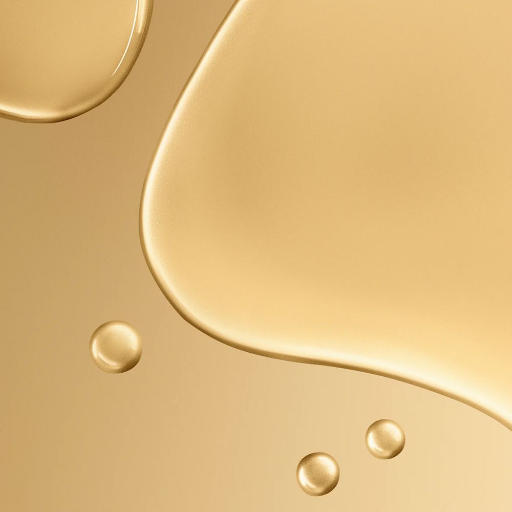 Goldfarbene Flüssigkeit mit Tropfen. Nahaufnahme. Helle, goldene Oberfläche.