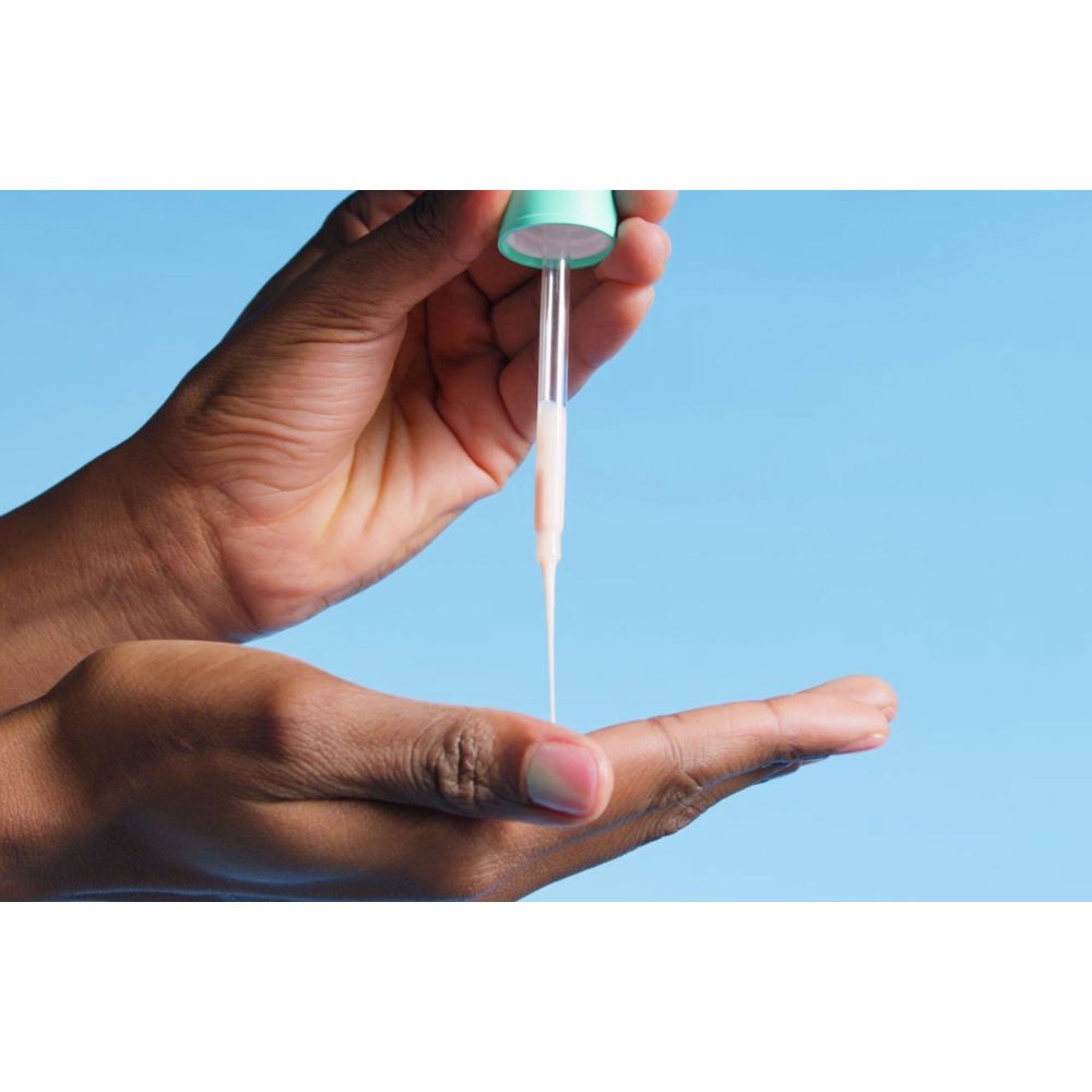 Hände halten Pipette mit Serum. Serum tropft. Blauer Hintergrund.