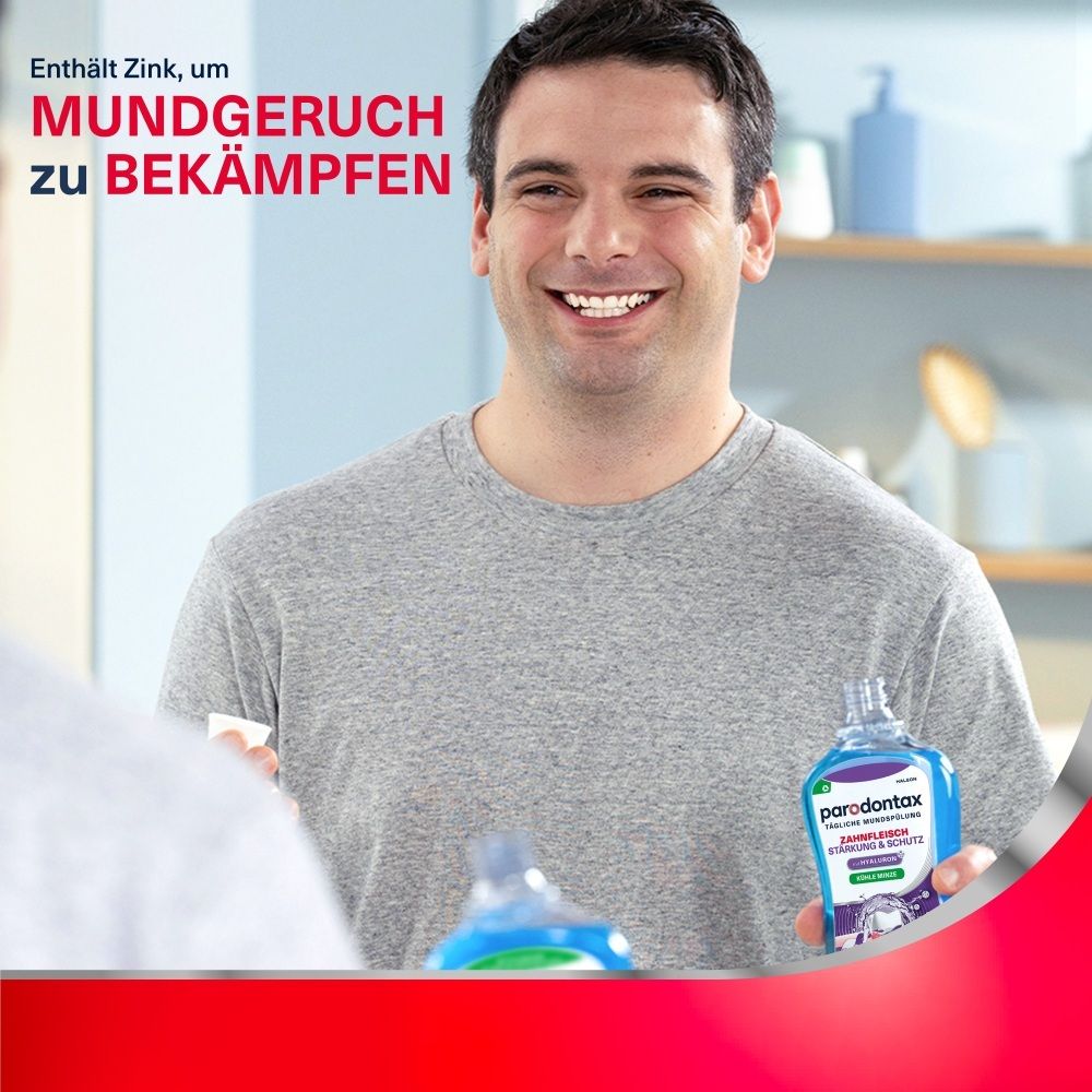 Mann hält Parodontax Mundspülung in der Hand und lächelt in einen Spiegel.