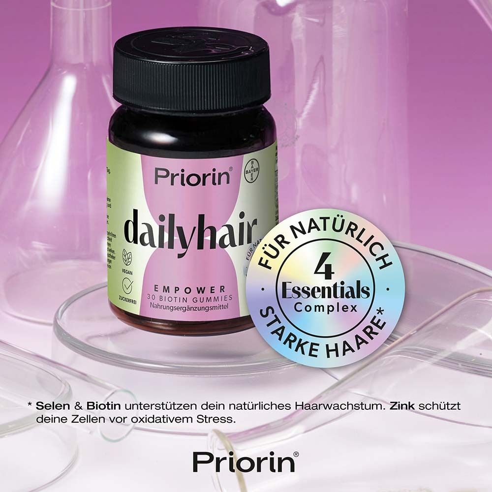 Flasche Priorin dailyhair vor Laborutensilien. Aufdruck: 4 Essentials Complex für natürlich starke Haare.