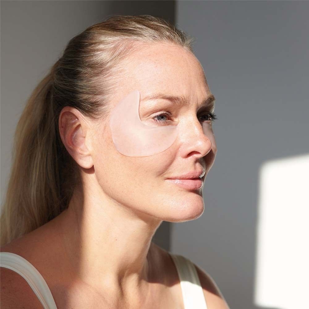 Frau mit Augen-Schläfen Pad auf dem Gesicht. Das transparente Pad bedeckt das Auge und die Schläfe. Helle Umgebung.