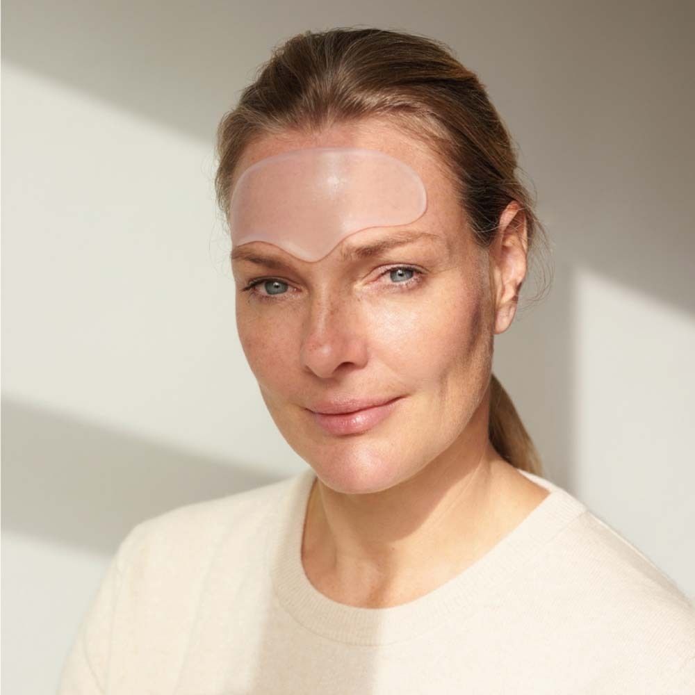 Frau mit Stirn Pad auf der Stirn. Helles, ovales Pad. Frau mit blonden Haaren und hellem Teint.