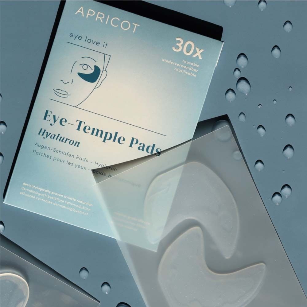 Verpackung mit Augen-Schläfen Pads und Pads. Marke APRICOT. Aufschrift: Eye-Temple Pads Hyaluron. Pads liegen daneben.