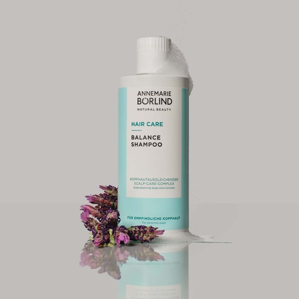 Flasche mit Shampoo und Lavendelblüten. Schaum umgibt die Flasche. Aufschrift: ANNEMARIE BÖRLIND, HAIR CARE, BALANCE SHAMPOO.