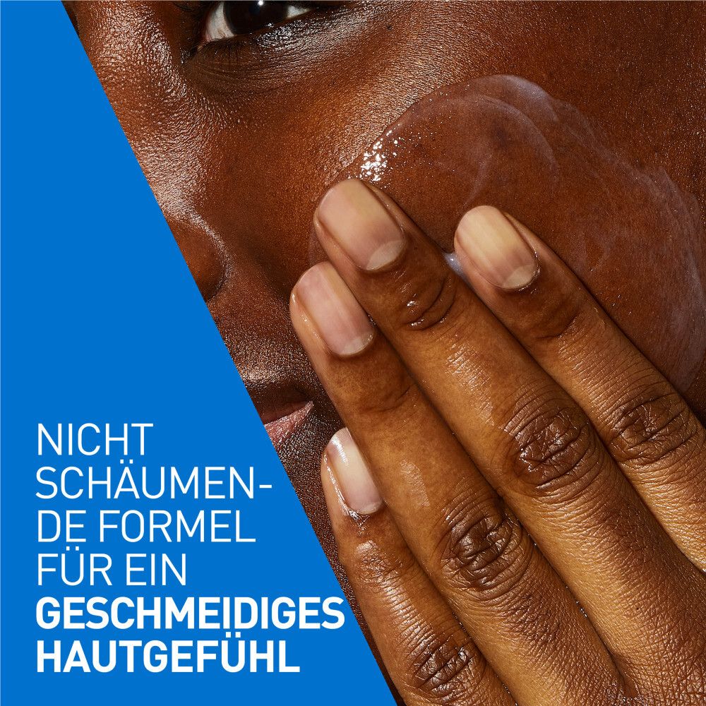 Hände tragen weiße Flüssigkeit auf das Gesicht auf. Nicht schäumende Formel. Blauer Hintergrund.
