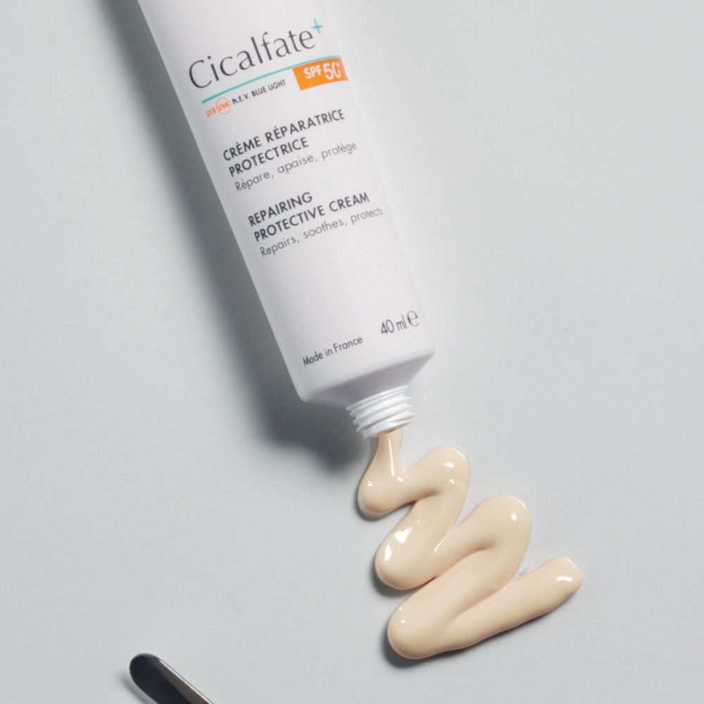Avène Cicalfate+ Creme SPF 50+ mit einer Spur auf grauem Hintergrund.
