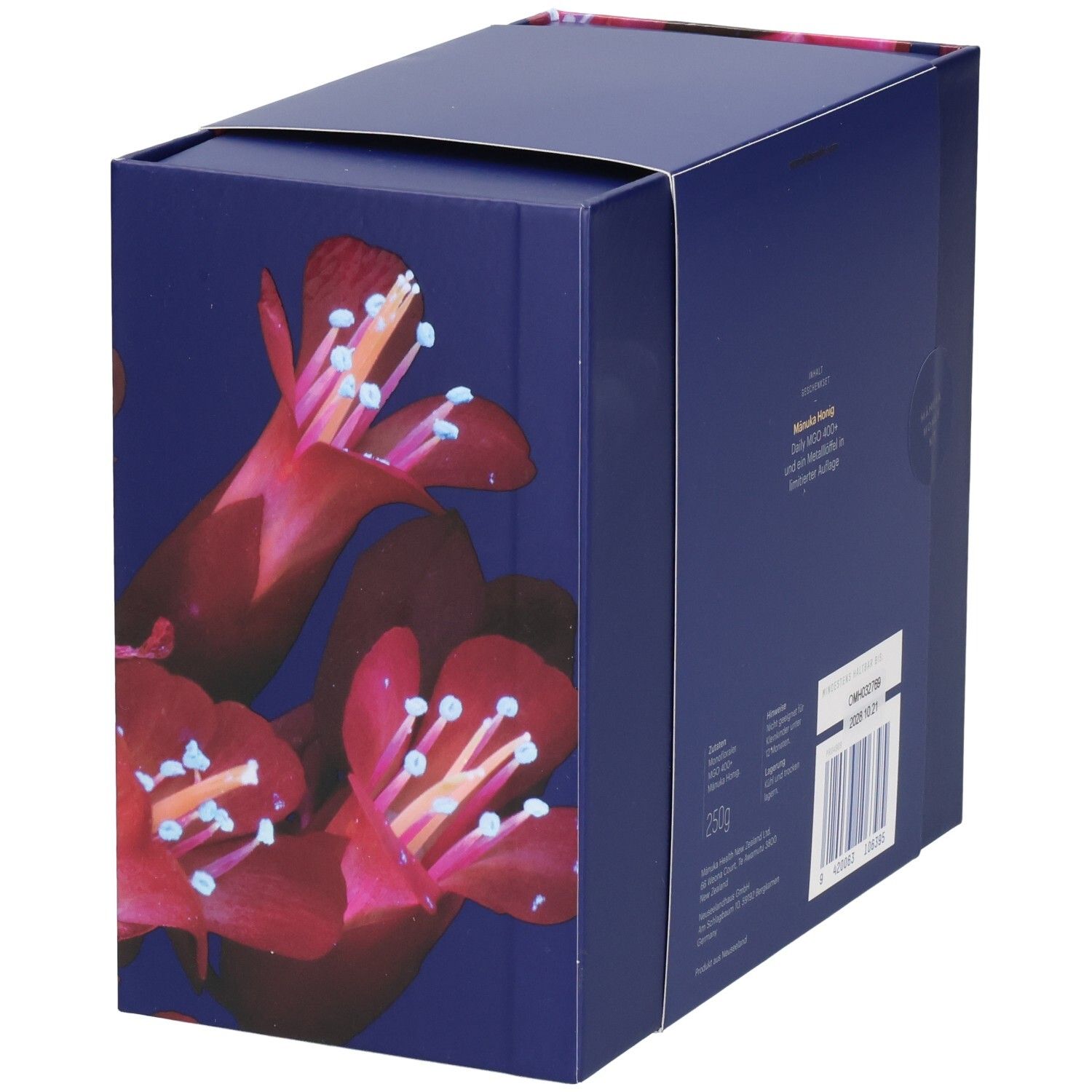 Geschenkbox mit floralem Muster. Text: Manuka Honig, MGO 400+. Barcode und Produktinformationen.