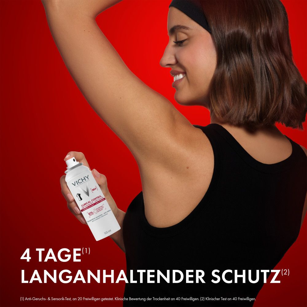 Frau sprüht Achsel mit Vichy Clinical Control Deo Spray. Roter Hintergrund. Text: 4 Tage langanhaltender Schutz.