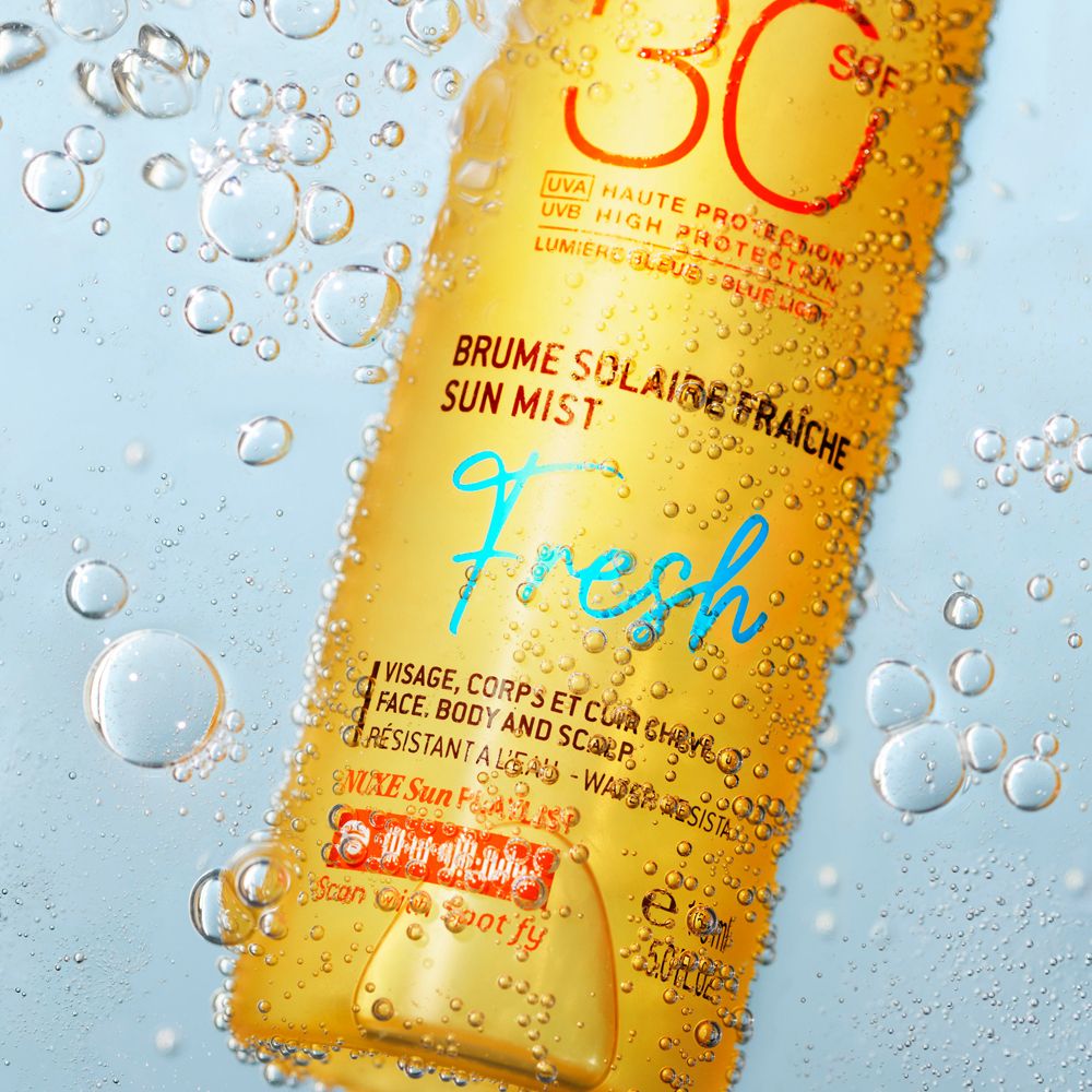 Sonnennebel-Spray im Wasser. Text: SPF 30, Brume Solaire Fraîche, Fresh. Für Gesicht, Körper und Kopfhaut. Wasserfest.