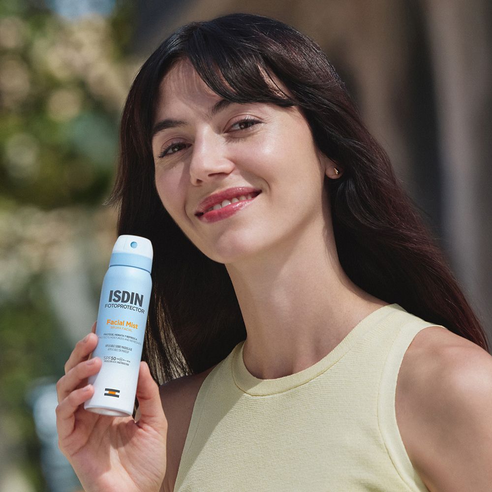 Frau hält ISDIN Fotoprotector Facial Mist Sonnenspray LSF 50.