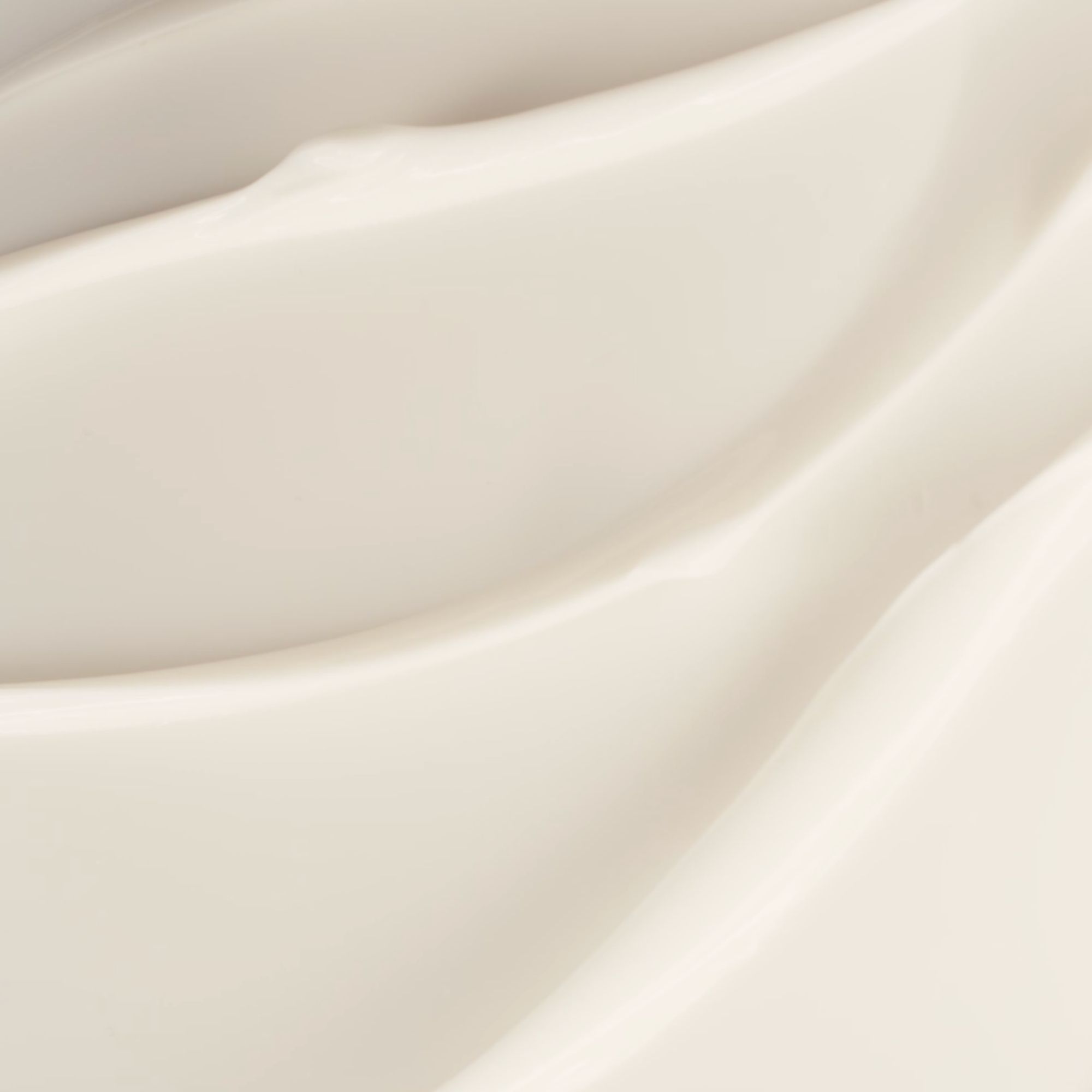 Nahaufnahme einer cremefarbenen, glatten Substanz mit wellenförmigen Strukturen.
