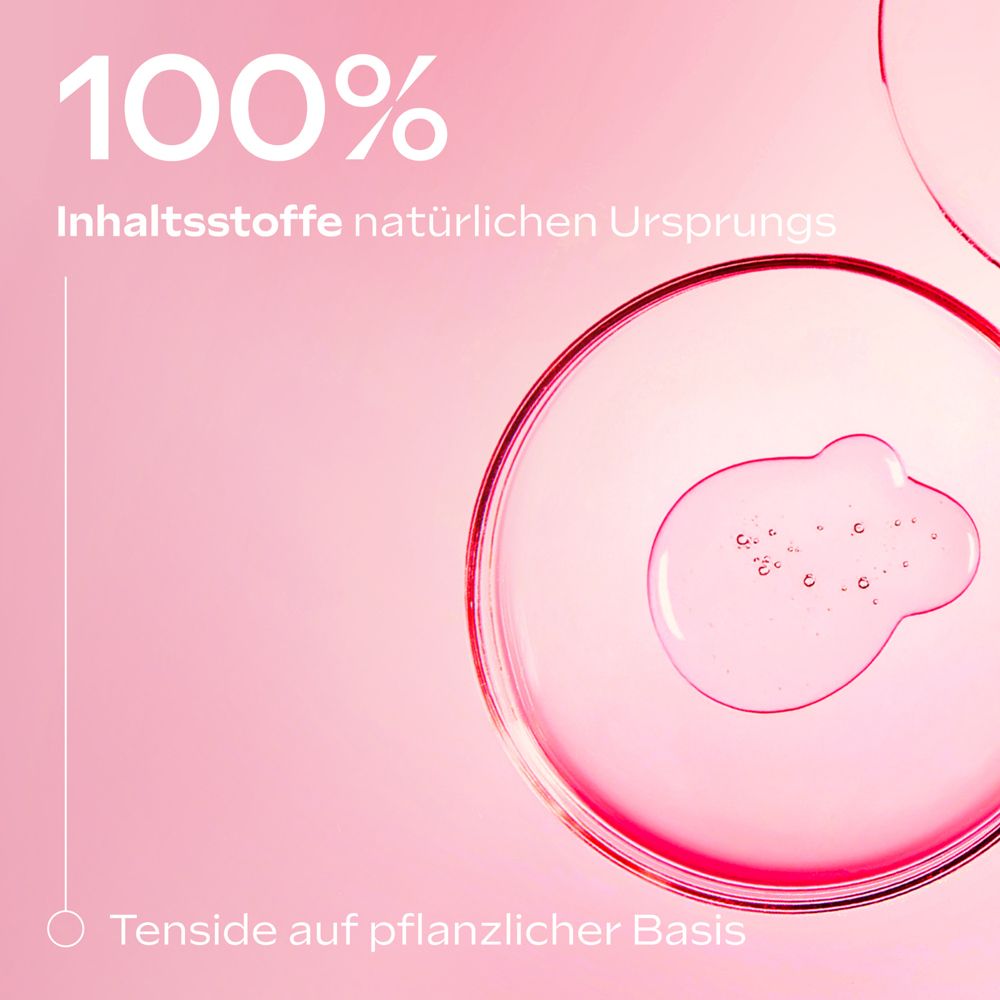 Nahaufnahme von Flüssigkeit in runden Behältern. Text: "100% Inhaltsstoffe natürlichen Ursprungs". Text: Tenside auf pflanzlicher Basis.