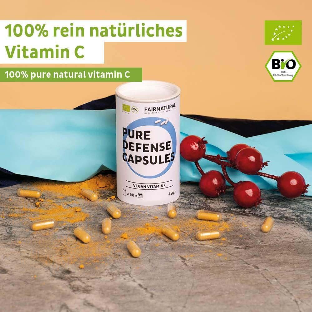 Produktverpackung mit Kapseln und Früchten. Dose mit Aufschrift: Pure Defense Capsules, Vegan Vitamin C. Bio-Siegel. Gelber Hintergrund.
