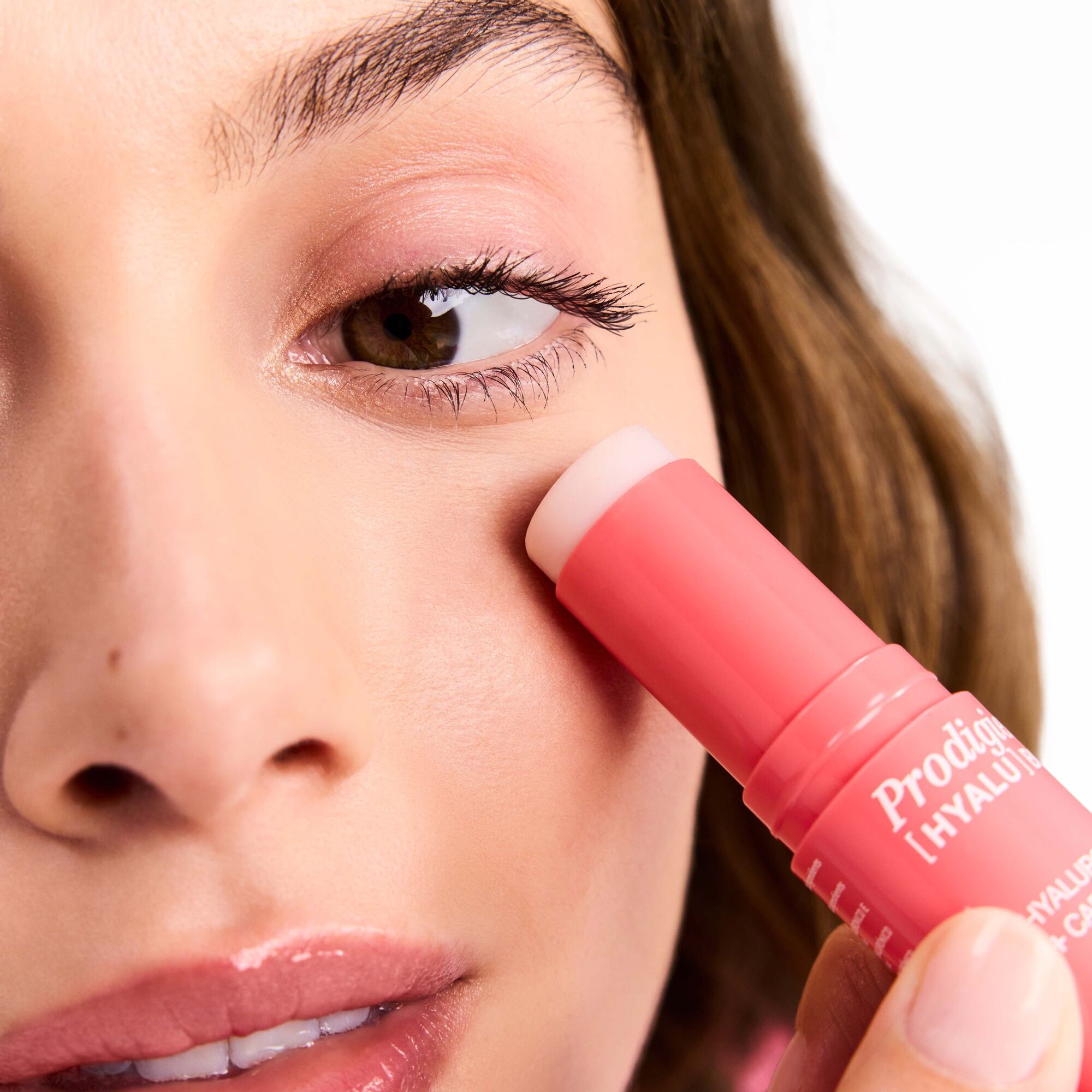 Nahaufnahme einer Frau, die den pinkfarbenen Stick unter dem Auge verwendet.