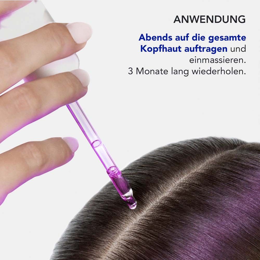 Eine Hand hält eine Pipette mit lila Serum über einer Kopfhaut.