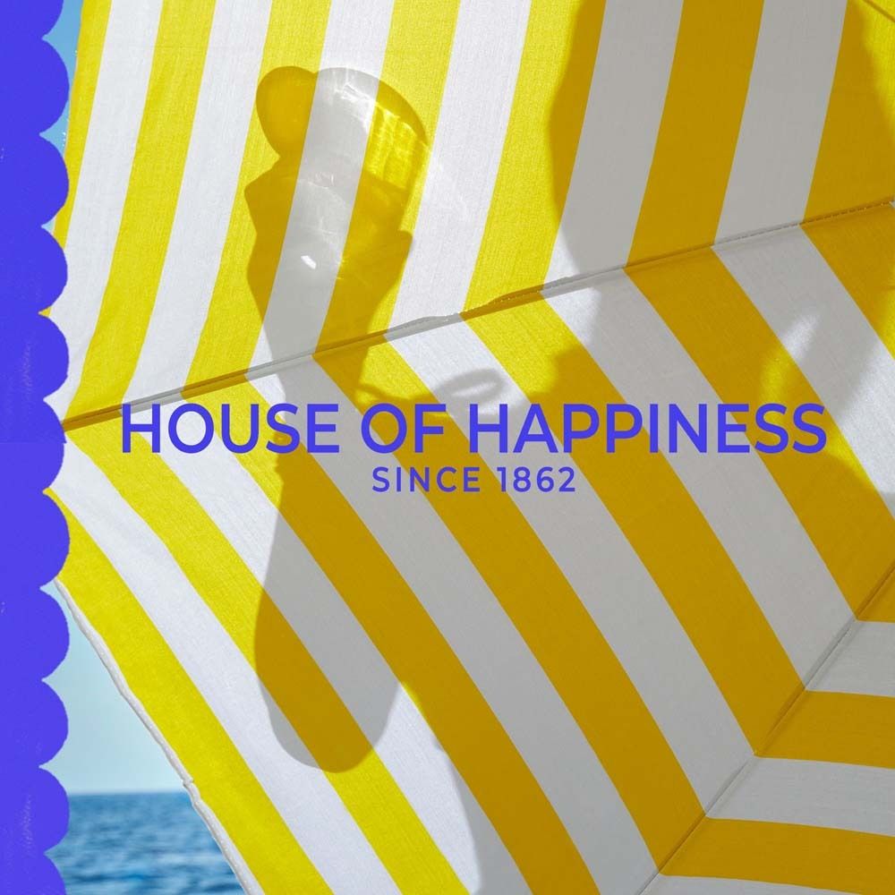Gelb-weiß gestreifter Sonnenschirm. Text: House of Happiness, Since 1862.