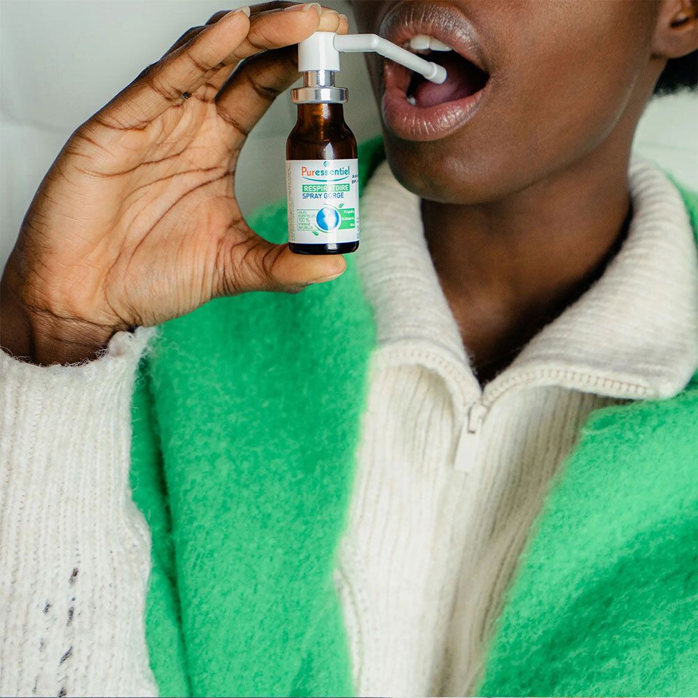 Personne tenant un flacon marron avec vaporisateur blanc. PURESSENTIEL RESPIRATOIRE SPRAY GORGE. Vaporisateur dans la bouche.