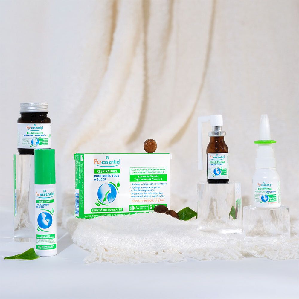 Différents produits PURESSENTIEL. Flacons, sprays et emballages. Sur des blocs de verre et fond blanc.