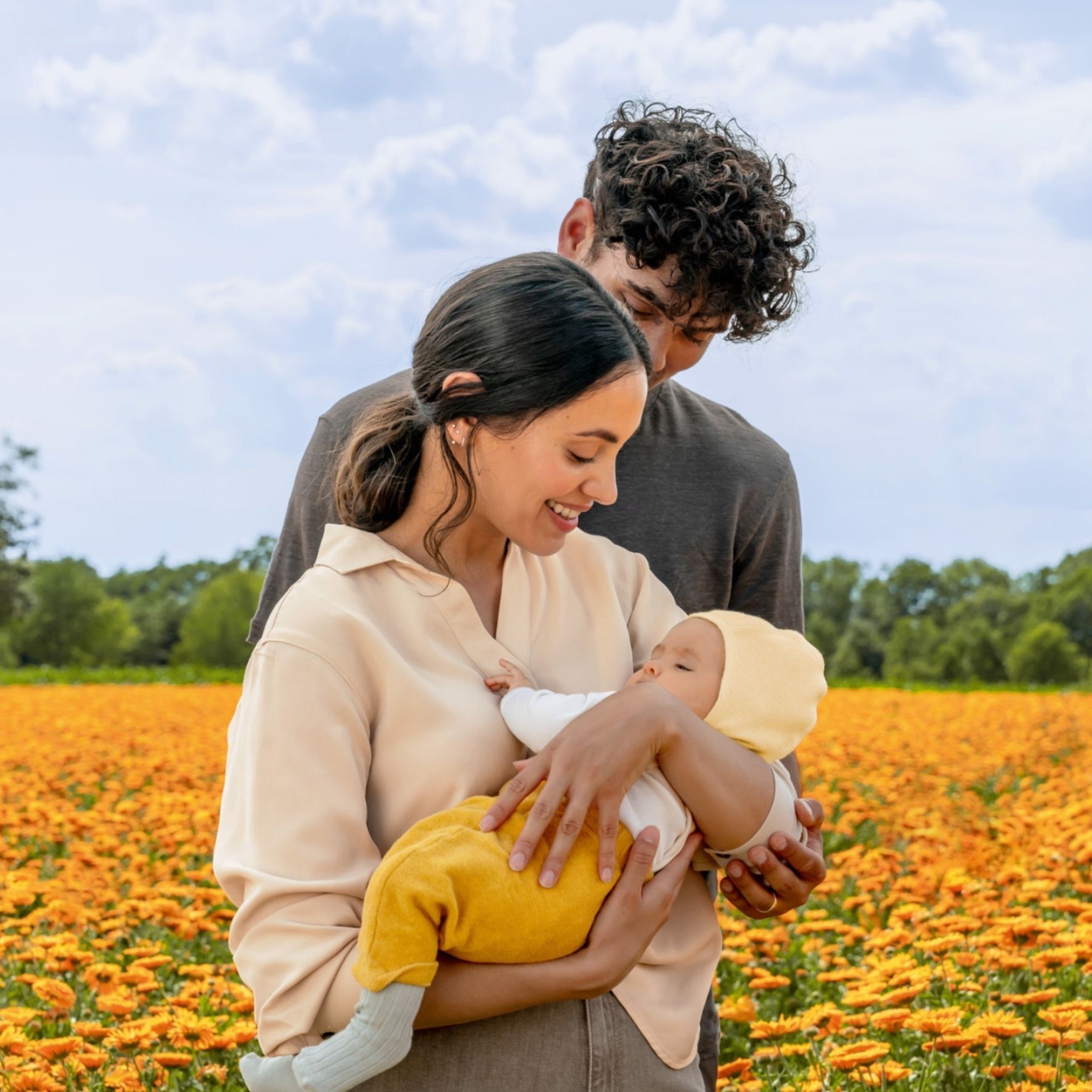 Famille avec bébé dans un champ de fleurs de Calendula. La mère tient le bébé.