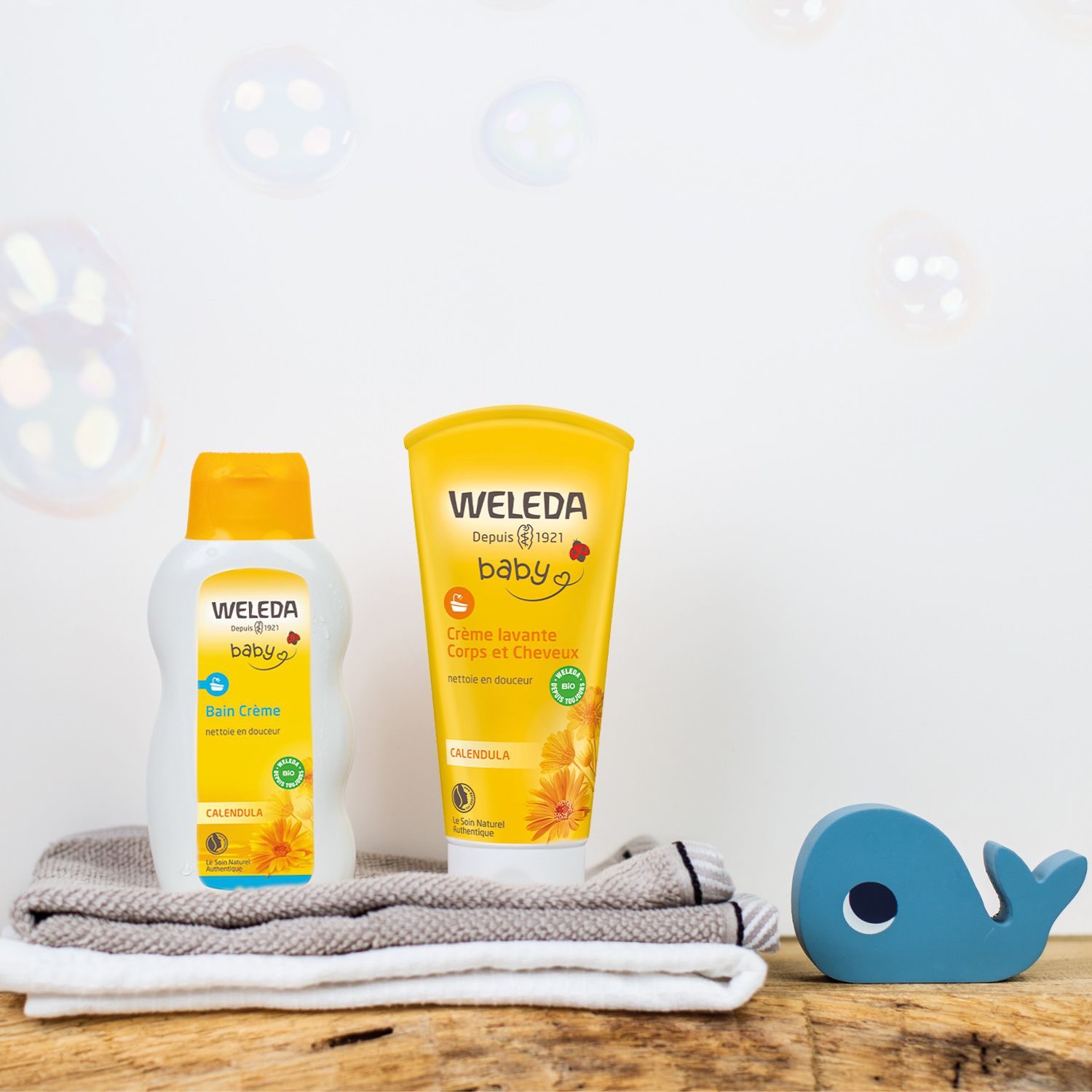 Zwei Weleda-Produkte neben einem Wal-Spielzeug. Links: Flasche. Rechts: Tube.
