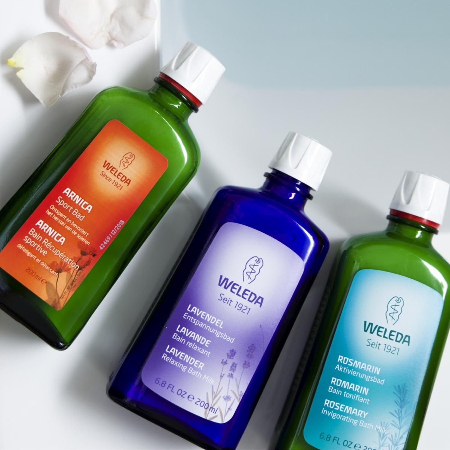 Drei Flaschen, darunter eine violette mit dem Produktetikett. Weitere Flaschen in Grün mit anderen Produktnamen.
