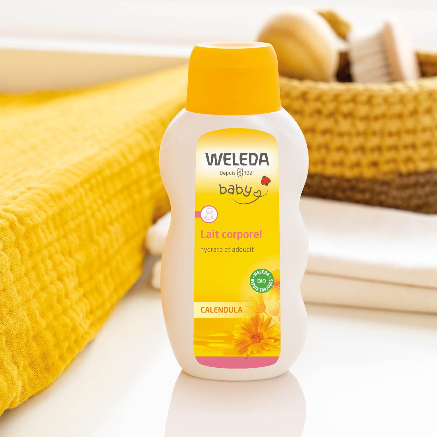 Weleda Baby-Ringelblumen-Körpermilch. Flasche auf gelbem Untergrund. Text: Calendula, Lait corporel, Weleda.