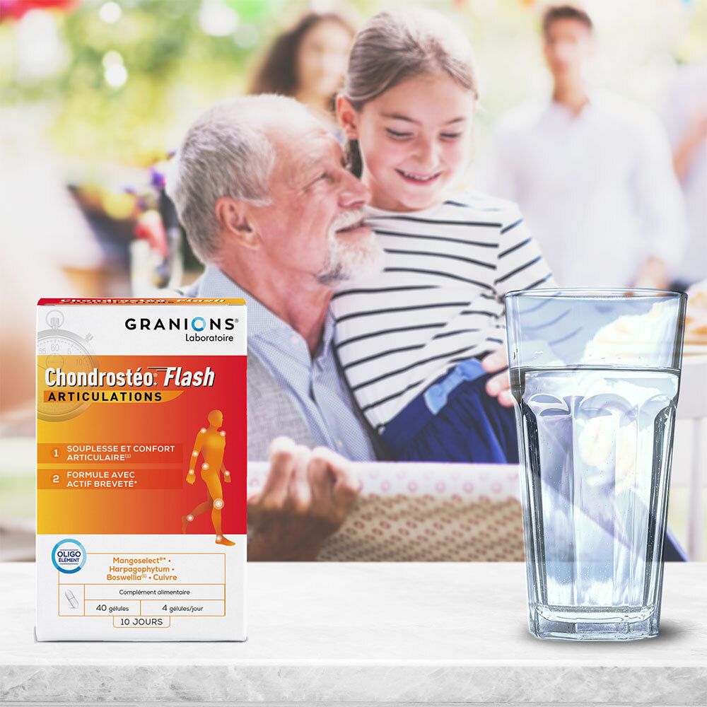Granions Chondrostéo Flash Articulation-Schachtel neben einem Glas Wasser. Im Hintergrund eine Familie.