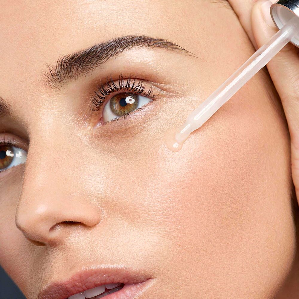Close-up van een vrouw die serum op haar huid aanbrengt met een applicator.