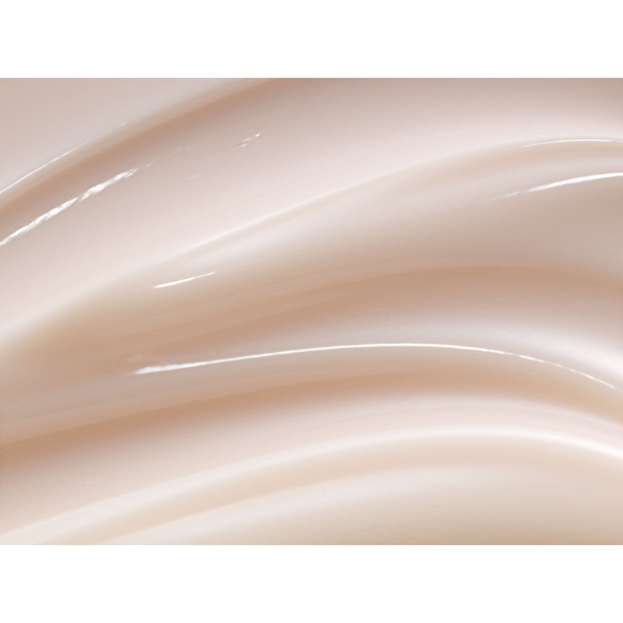 Nahaufnahme von cremiger, beiger Creme. Wellenförmige Textur mit glänzenden Reflexen.