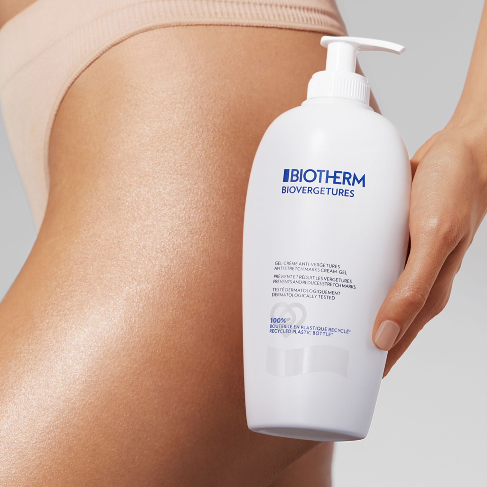 Frau hält Flasche neben Bauch. Flasche: Biotherm, Biovergetures. Weißes Gel-Creme.