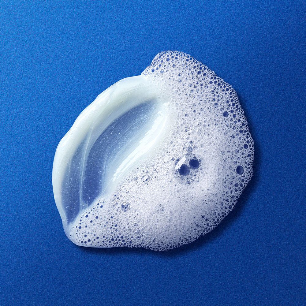 Klecks Reinigungsprodukt mit Schaum auf blauem Hintergrund.