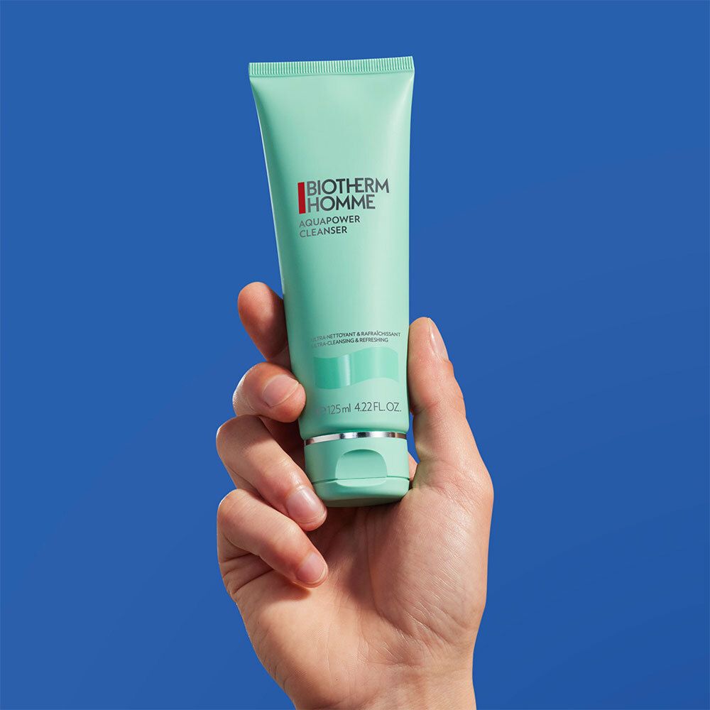 Hand hält türkisfarbene Tube mit BIOTHERM HOMME AQUAPOWER CLEANSER-Logo. 125ml 4.2 fl.oz.