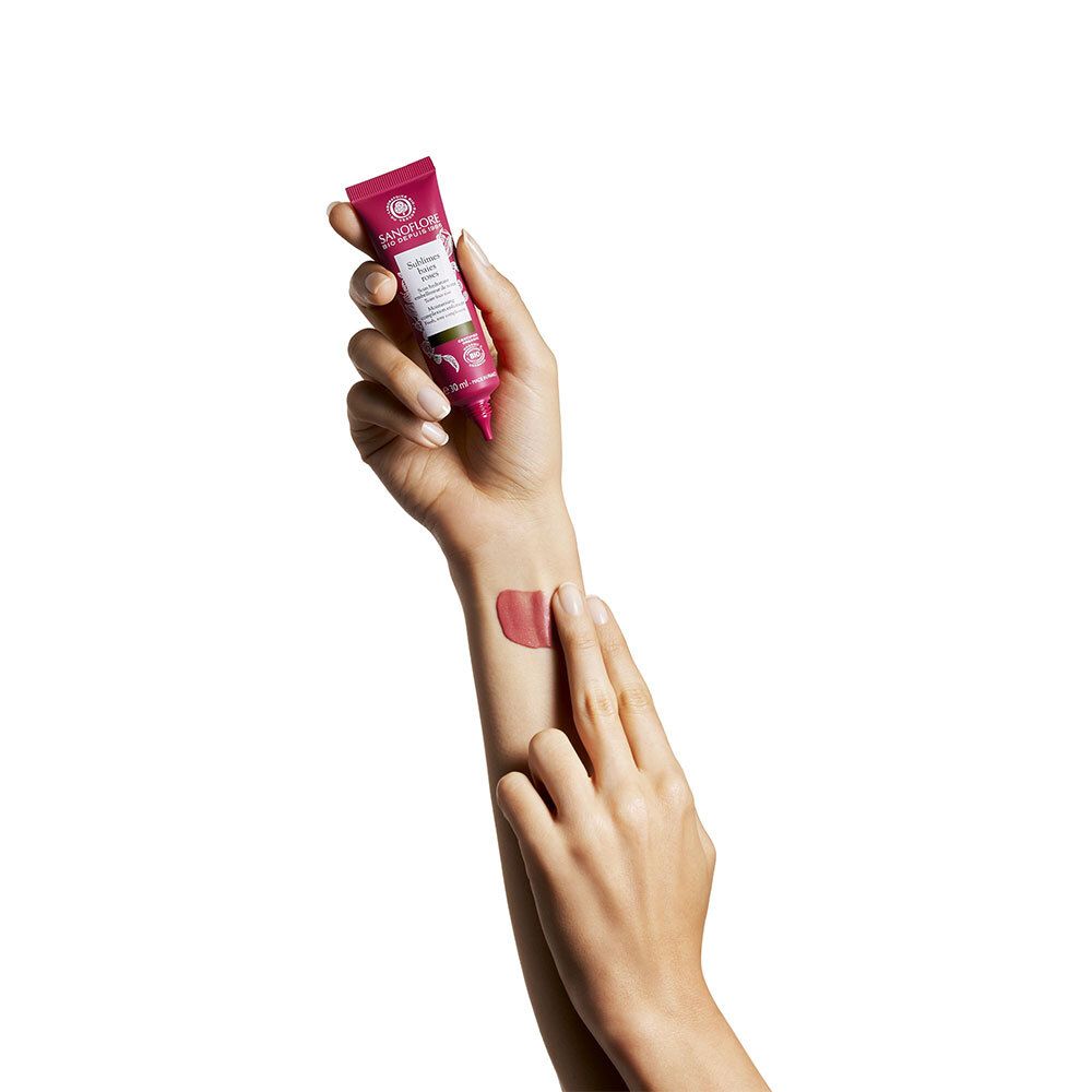 Main avec produit. Teinte rose sur la peau. Sanoflore, Sublimes baies roses.
