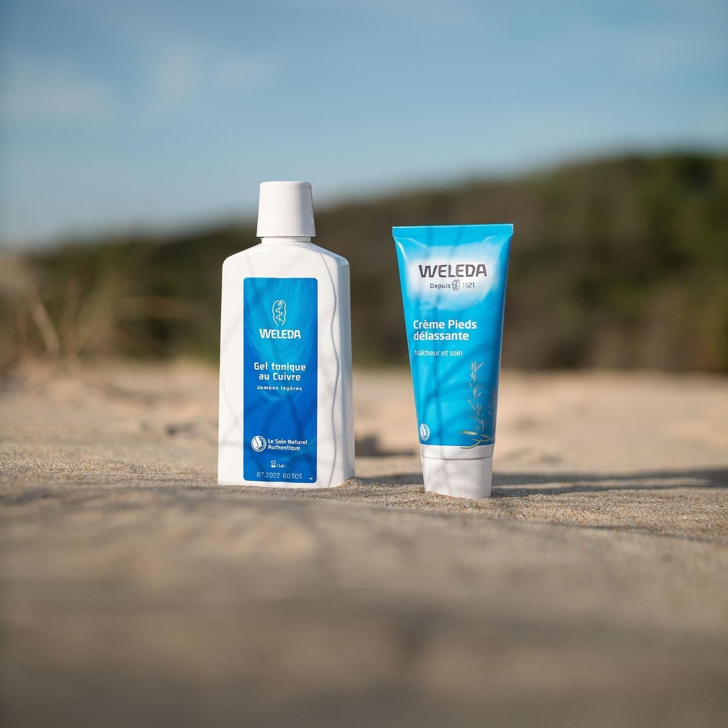 Gel et crème Weleda sur sable. Texte: Gel tonique au Cuivre. Crème pieds délassante.