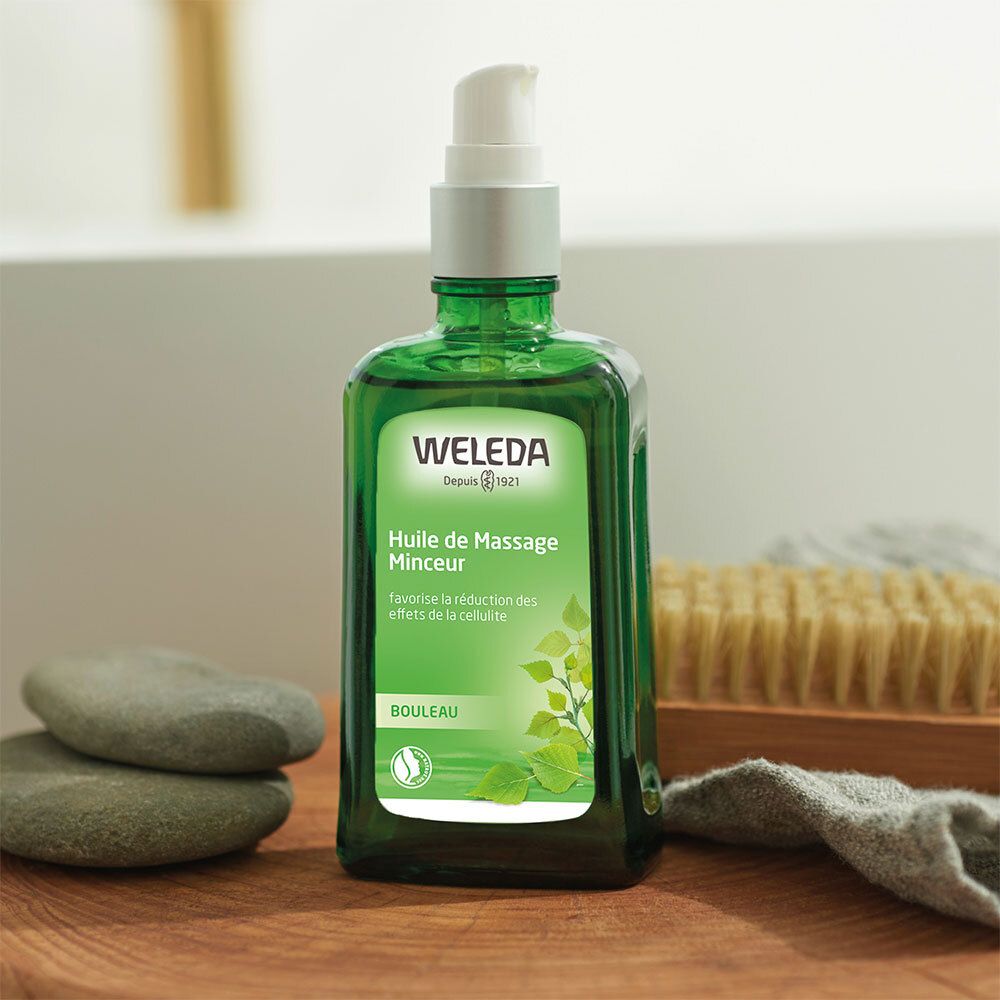 Flacon en verre vert avec pompe à côté de pierres et d'une brosse. Nom et logo du produit visibles.
