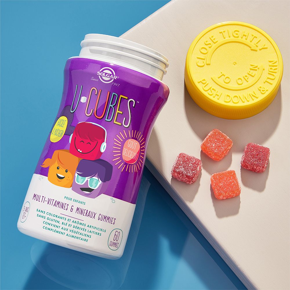 Flacon violet ouvert avec bouchon jaune et bonbons gélifiés. Inscription : U-CUBES. 60 gummies. Pour enfants.