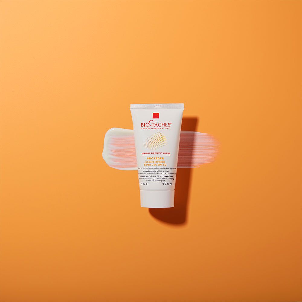 Tube BIO-TACHES® SOLAIRE INVISIBLE SPF 50 avec trace de crème. Fond orange.
