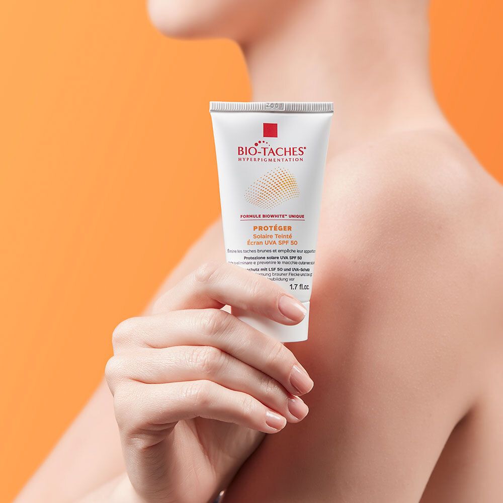 Tube BIO-TACHES® SOLAIRE LSF 50 tenu par une personne. Tube blanc avec logo et texte.