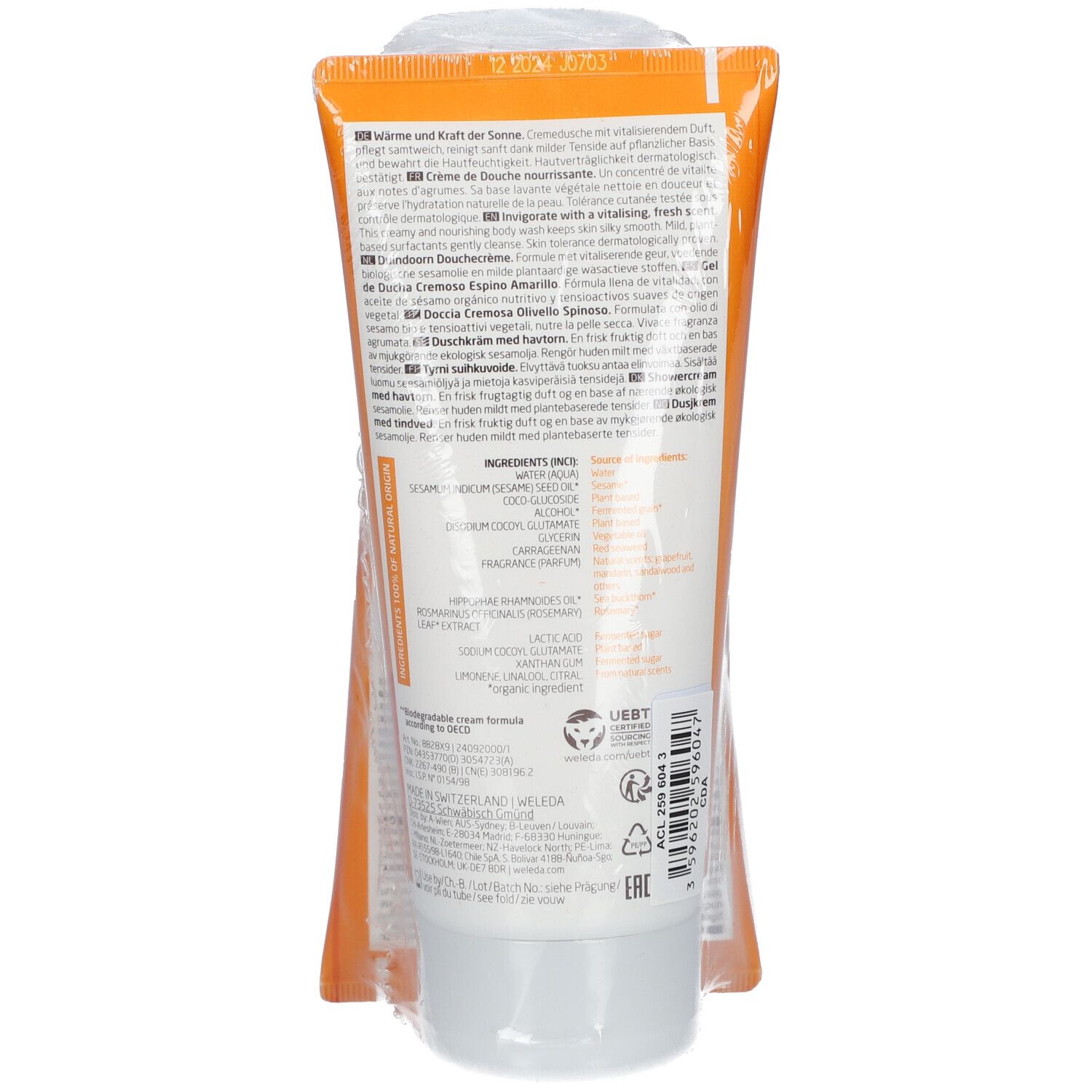 Tube de crème de douche Weleda, étiquette orange. Texte multilingue. Sceau et symbole de recyclage.