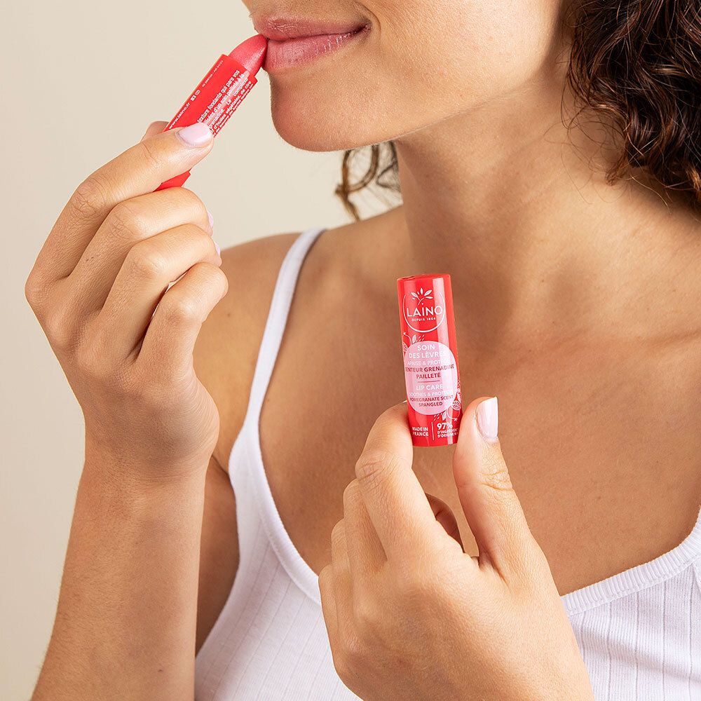 Frau trägt roten Lippenpflegestift auf. Ein weiterer Stift wird gehalten. Produkt: LAINO Lippenpflege.