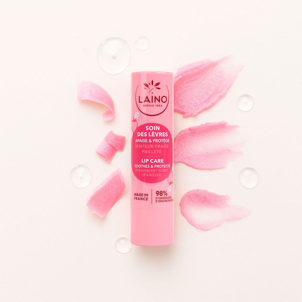 Rosa Lippenpflege-Stift mit rosa Glitzer-Effekt und Wassertropfen. Text: LAINO, Soin des Lèvres, Apaisé & Protège, Senteur Fraise, Pailleté, Lip Care, Soothes & Protects.