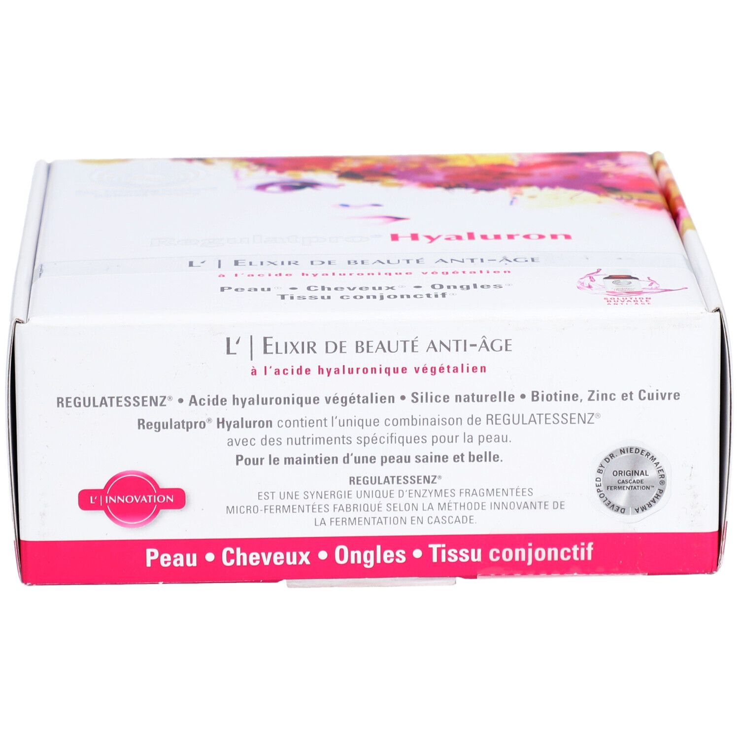 Weißer Karton mit rosa Akzenten. Text: L'Elixir de Beauté Anti-Âge, Regulatessenz Hyaluron. Enthält Biotin, Zink und Kupfer. Siegel.
