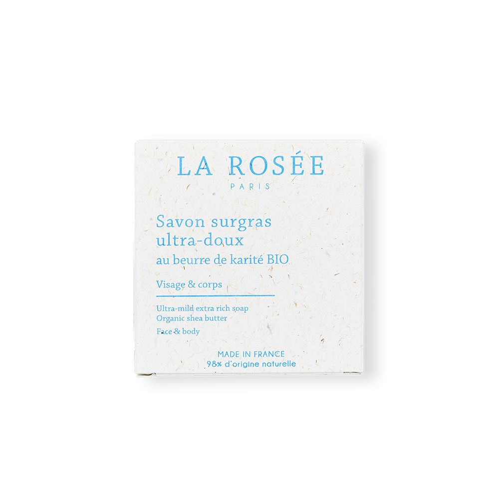Bloc de savon carré avec texte bleu. En haut, LA ROSÉE PARIS. En dessous : Savon surgras ultra-doux au beurre de karité BIO.