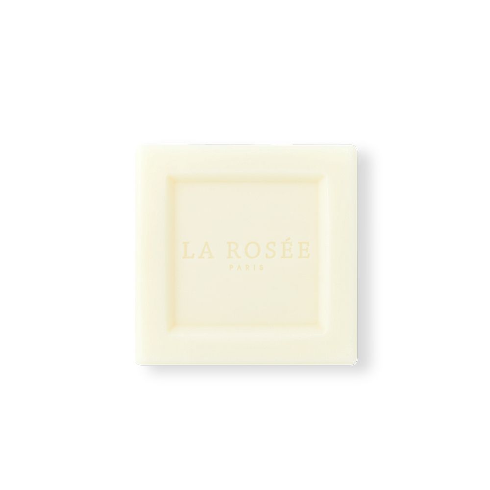 Bloc de savon carré, couleur crème, avec LA ROSÉE PARIS en relief. Le bloc est carré avec des bords arrondis.
